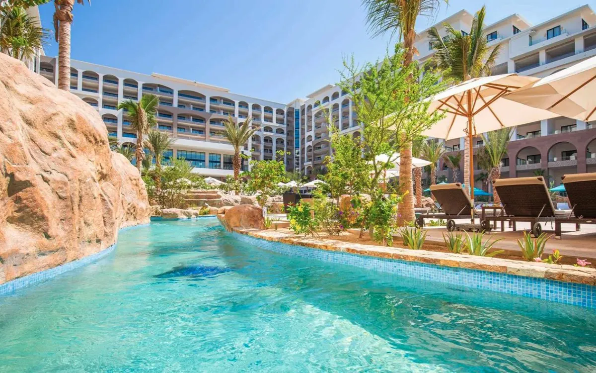 Resort pool with a lazy river, palm trees and lounge chairs in Cabo San Lucas
