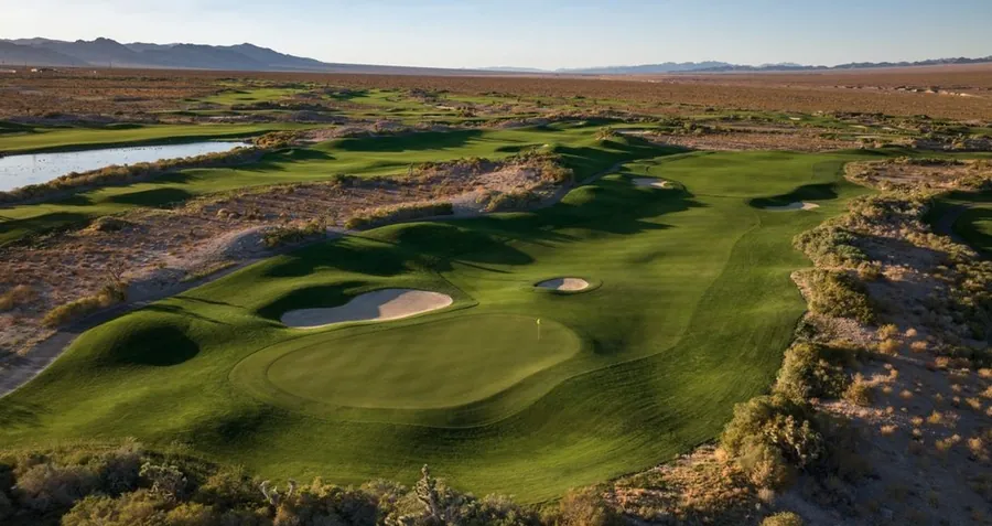Aerial view of a green and bunkers framed by desert at golden hour