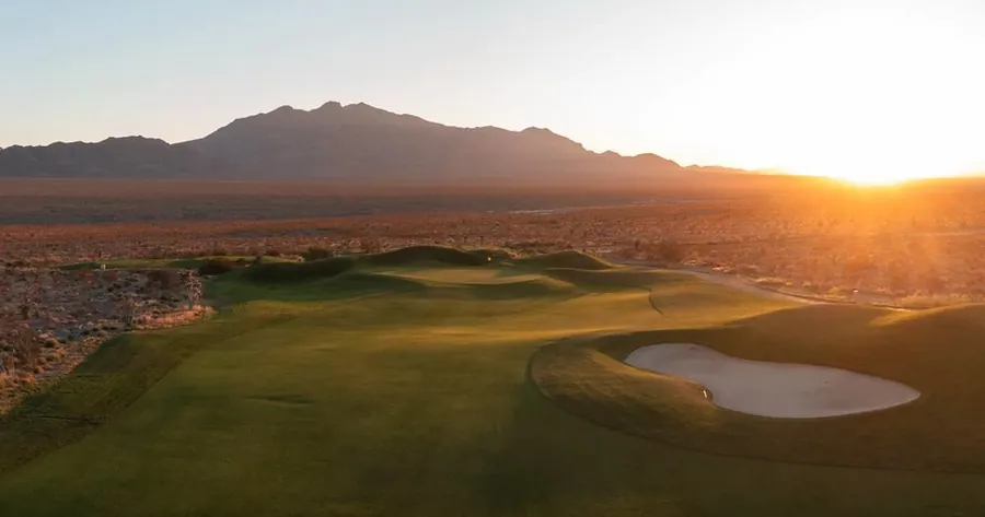 Fairway and bunker at sunrise with desert mountains behind